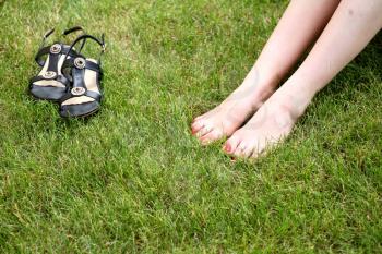 Womans bare feet on the fresh green grass and shoes