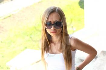 Blond woman in jeans and dark glasses standing on an outdoor summer patio