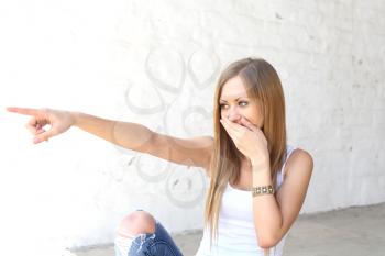 Blonde woman cover mouth with hand and pointing at someone