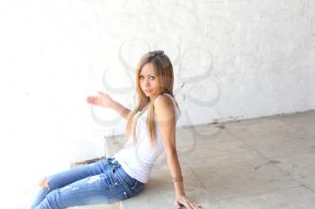 Outdoor photo of pretty girl sitting on the floor in grungy setting.