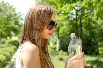 Profile of beautiful woman going to drink some water  fron plastic bottle after workout