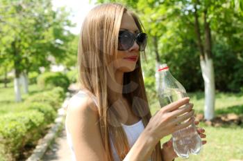 Profile of beautiful woman going to drink some water  fron plastic bottle after workout