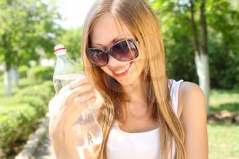 Portrait of beautiful smiling woman with bottle of water, outdoors