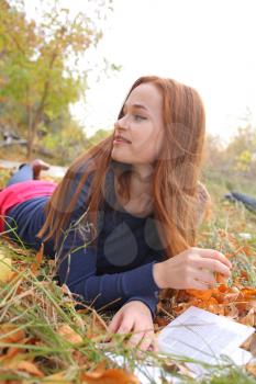 Redhead girl at outdoor reading autumn park