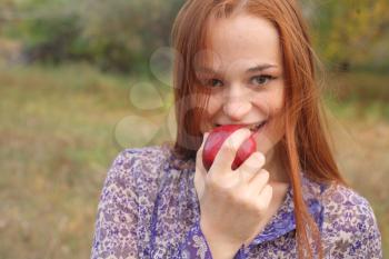 portrait of young woman holding red apple in hand outdoor