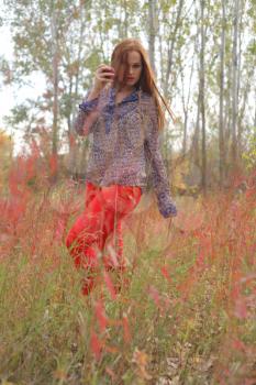 woman in autumn park in red grass, outdoor portrait