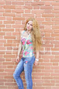 Beautiful woman with long blond hair standing against brick-wall