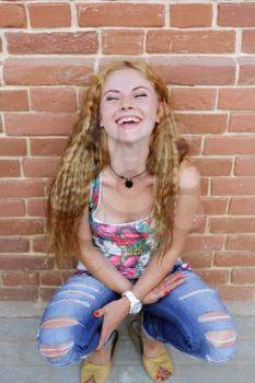 The girl with long hair sitting near wall and having fun
