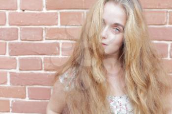 portrait of beautiful young casual girl before the brick wall. Head and shoulders. Pastel colors