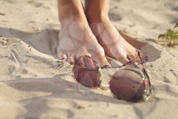 Woman feet with dark pedicure relaxing on the sand