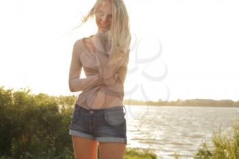 blond girl standing near river against sun