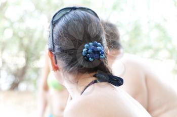 Woman looking away with blue scrunchy on the hairs, summer fores
