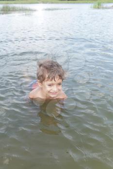 Cute little boy playing in water outdoors on summer day