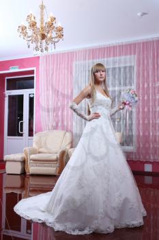 beautiful blond bride in classic white dress in the room