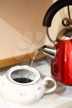 red kettle with black and silver elements. Water pouring into the teapot