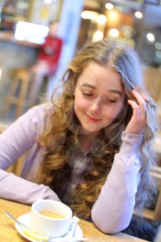 beautiful young woman sitting in a cafe drinking coffee