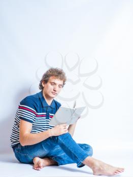 Portrait of a young man holding an open book, in studio on gray background