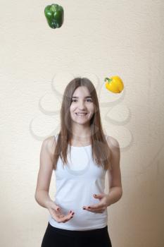 blond girl having fun with colorful peppers on the beige background. Healthy nuitrition foood concept