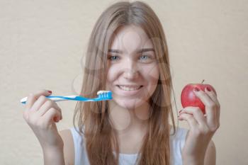 Dental Hygiene Concept - A head and shoulders view of a blond woman with teeth brush and red apple