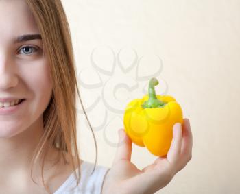 beautiful girl with yellow sweet pepper - organic food and health concept. Half of the face