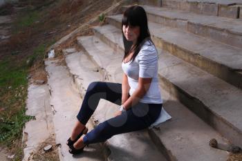 Portrait of a beautiful young woman, model of fashion, in a garden stairs.