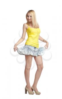 charming long-haired blonde in a yellow tank top and skirt white background