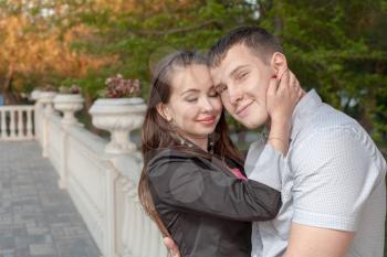 Young couple in love - young man embracing his girlfriend outdoors. Closed eyes