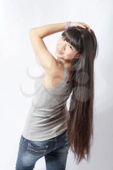 back view of standing young beautiful Asian woman in tank top and jeans torso shot. Teen watching. Rear view. Backside view of person. Shot over white background.