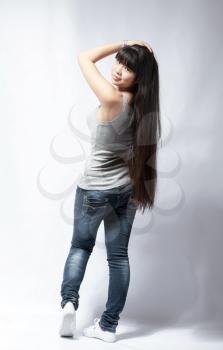 back view of standing young beautiful Asian woman in tank top and jeans full body . Teen watching. Rear view. Backside view of person. Shot over white background.