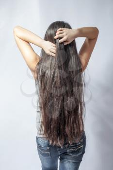 Girl with long fair hair from back, on white background.