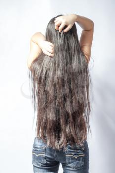 Girl with long fair hair from back, on white background.