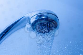 Photograph of a shower head water drops with bokhe sparkles and streams of water. Shower and flying water drops.