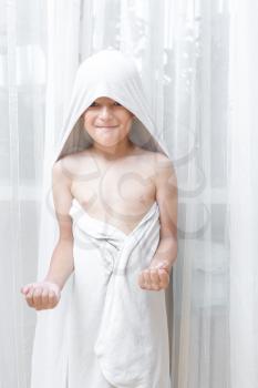 Portrait of a six year old boy with a serious expression on his face and a towel on his head, expressing positivity