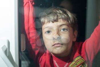 Little boy looking through window glass indoors