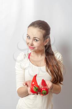 beautiful young blond woman with red peppers against white background