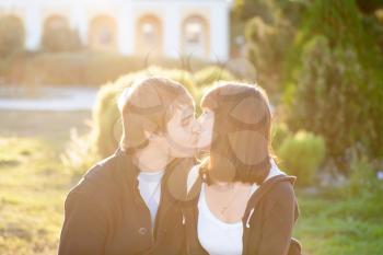 Happy couple against the background of park kissing, backlit composition, togetherness concept, love and tenderness