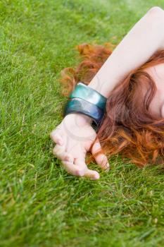 very  pretty red headed women laying on the fresh green grass and enjoy summertime