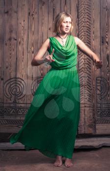 Cross processed colors romantic blond hair women in long green dress on the background of ancient wood door art posing
