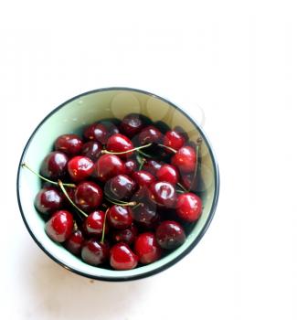 Crockery with ripe cherries on a white background.