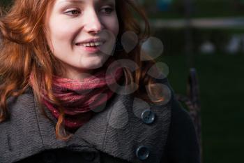 Portrait of the young 20s redhead women in autumn park. Smiling, part of the face