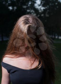 Face is hidden by hair. Sad 20s female outside close-up image. Portrait of a beautiful young 20s women in the park in evening.