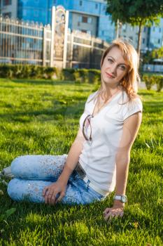blond sitting on the fresh grass against sun