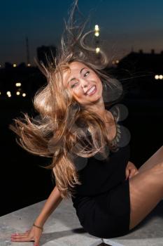 wind in hair. long haired blond women at night in city park