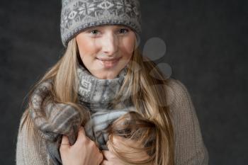 Sexy blond haired female smiling and looking at camera. Portrait of woman on dark background wearing woolen accessories