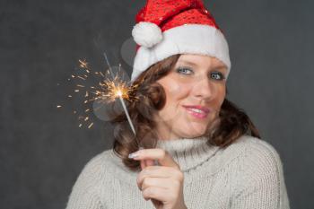 Front view of the Cute girl in Santa hat holding sparklers