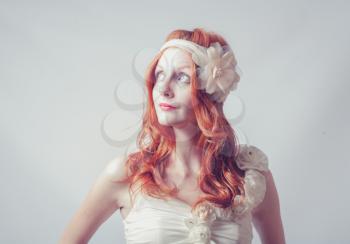 Redhead female looking up. Portrait of a beautiful red haired woman with flower in her hair. Fashion photo