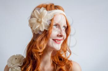 Portrait of smiling  a beautiful red haired woman with flower in her hair. Fashion photo