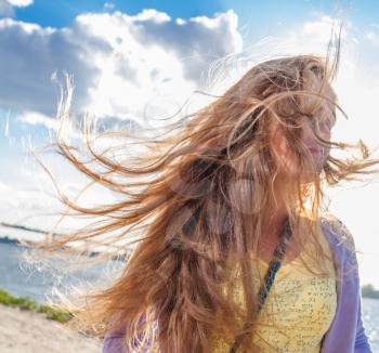 wind in hair. Candid shot of the long haired blonde female against sky with clouds