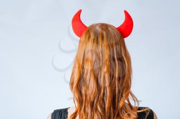 backview close up of a red haired girl with horns like a devil