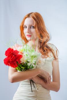 Vertical image of the redhead with bunch of flowers in studio on white